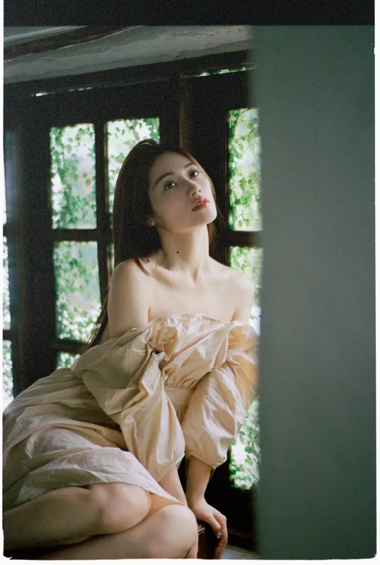 一位穿着连衣裙的年轻女子坐在窗户上