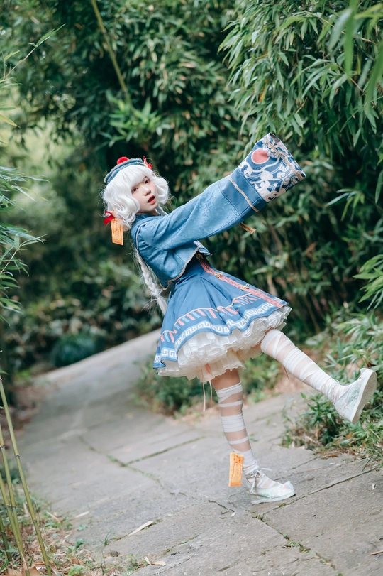 一位穿着蓝色连衣裙的小女孩正在花园里打着伞跳舞。