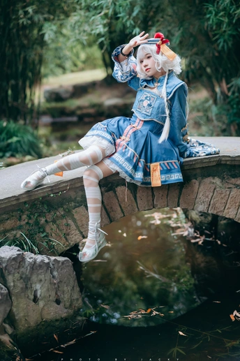 一个小女孩穿着服装坐在池塘上的桥上