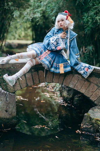 一个穿着服装的女孩坐在一条溪流上的桥上