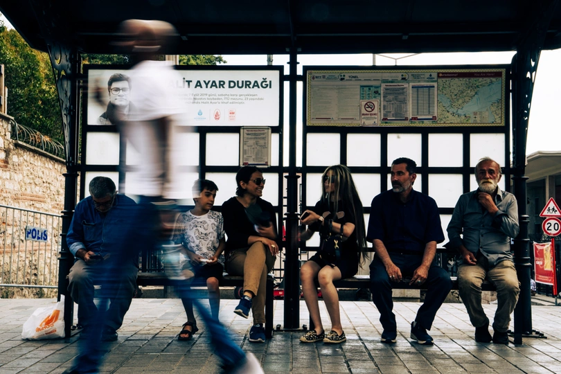 几个人坐在火车站的长椅上等待火车。