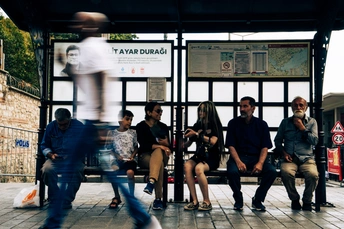 几个人坐在火车站的长椅上等待火车。