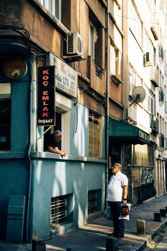 一条狭窄的巷子 有建筑物 一个人站在人行道上 一个人正在街上走。