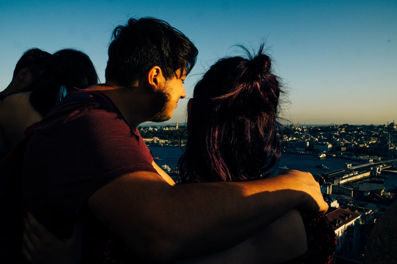 夕阳下 城市顶部的一个年轻男子和女子相拥。