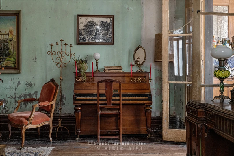一个充满旧家具和墙上钢琴的客厅和餐厅