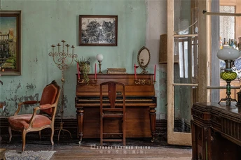 一个充满旧家具和墙上钢琴的客厅和餐厅