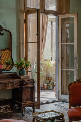 一个打开的门 一把椅子 一张带有镜子和盆栽的旧式桌子 在一个老房子里
