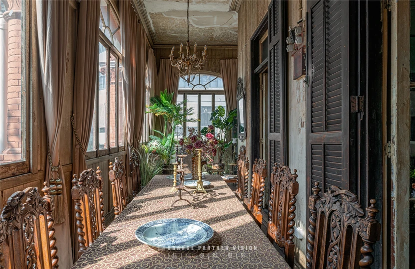 一个带有长桌和椅子的餐厅 有大型窗户和盆栽。