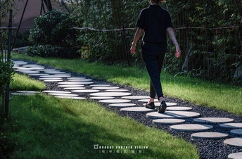 一个人和一个女人走在用鹅卵石铺成的小径上 一个带着伞的女人沿着小径走下来。