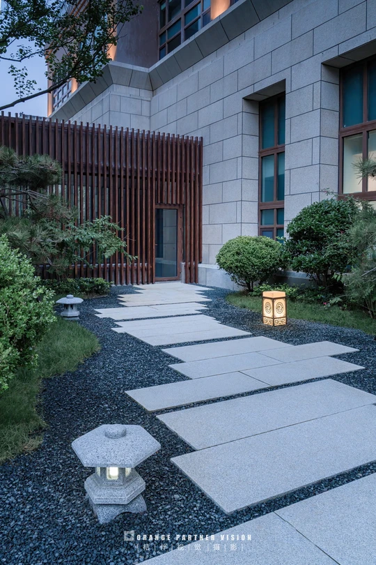 一座用石头建造的现代房屋 配有照明灯笼的步行道。