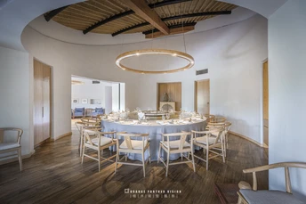 一个带有木地板的天花板拱顶的大餐厅 配有白色椅子与桌子。