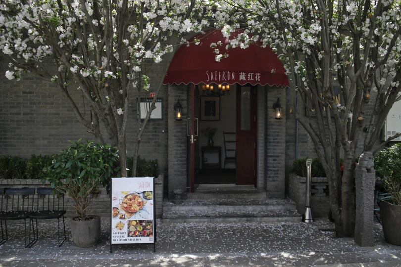 餐厅前面的入口处有建筑物前的招牌和开满白色花朵的树木。