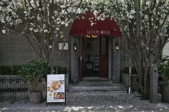 餐厅前面的入口处有建筑物前的招牌和开满白色花朵的树木。