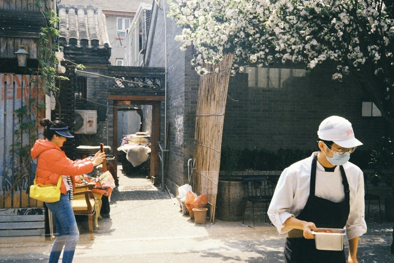 一个戴面具的男子走在一条小巷 一个戴面罩的女人走在街上。