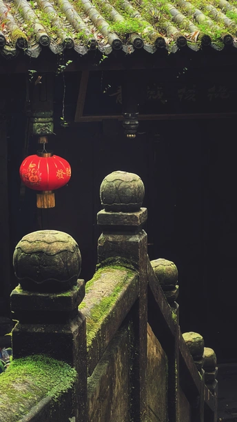 挂在长满青苔的建筑物屋顶上的红灯笼