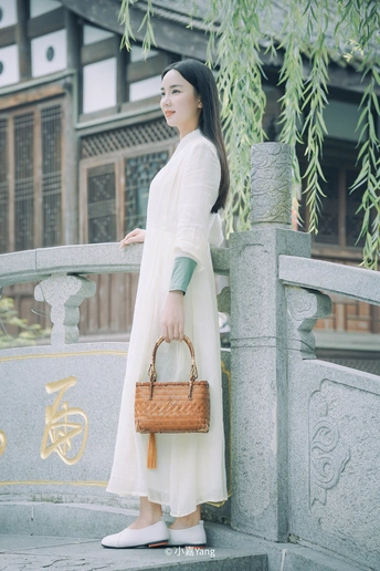 一个穿着传统连衣裙的年轻女子拿着一个白色袋子