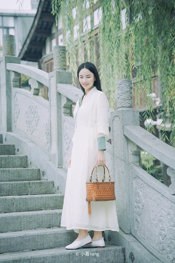 一个穿着白色连衣裙的年轻漂亮女人站在台阶上