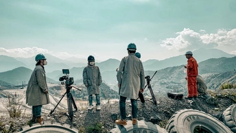 人们站在一个山坡上 有轮胎和相机。