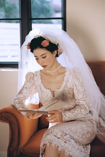 一位穿着婚纱和头纱的女士坐在椅子上读书