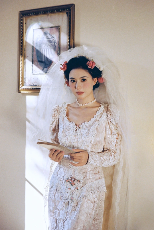一位穿着白色婚纱的年轻女子手持面纱站在门口