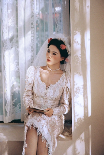 一个穿着白色婚纱的女人坐在窗户旁边
