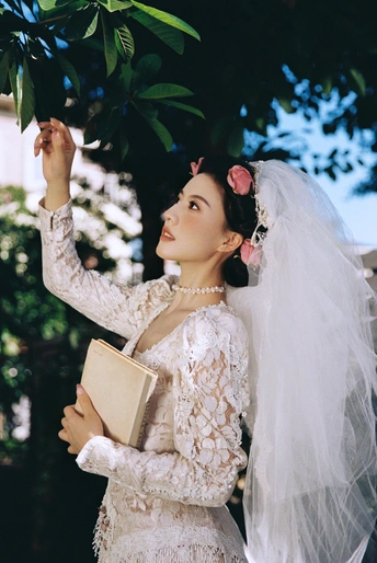 一位穿着婚纱和面纱的女子在外面的树上为她的婚礼竖立着。