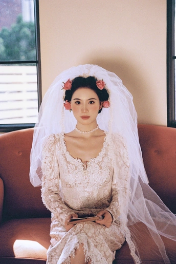 一位穿着白色连衣裙和头纱的女士坐在沙发上