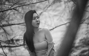 一位黑发年轻女子站在一棵棵树的森林中