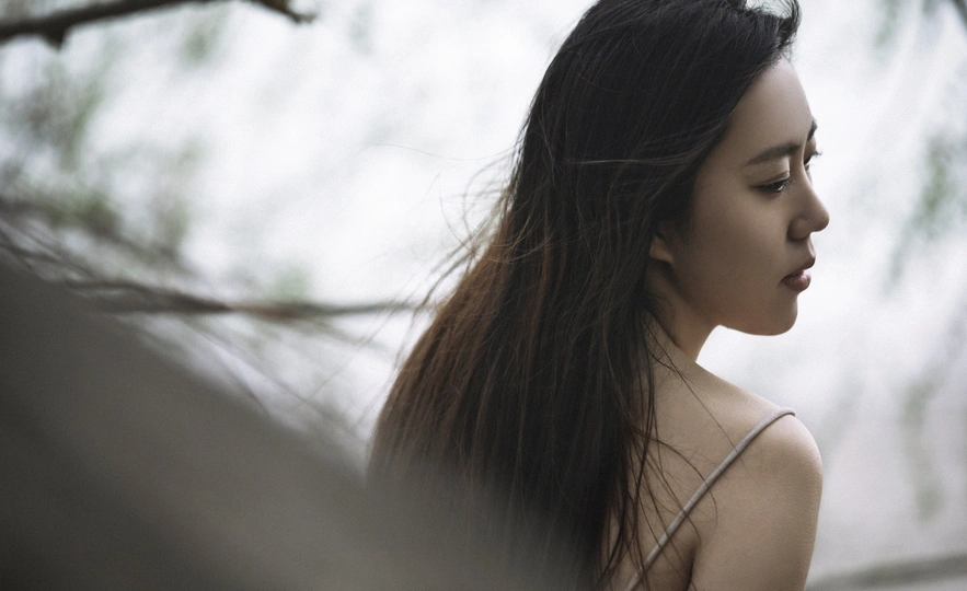 美丽的年轻女子长发站在一棵树下