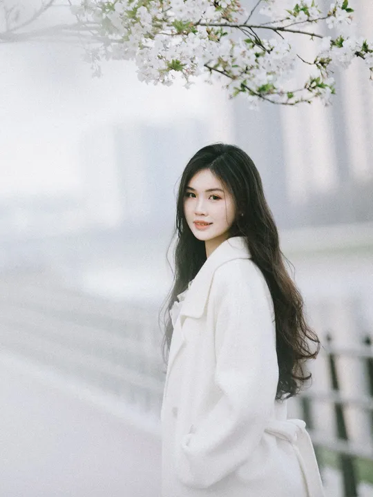 一位穿白大褂的女士站在樱花树下