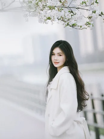 一位穿白大褂的女士站在樱花树下