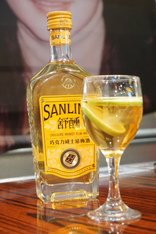 一杯白葡萄酒和一瓶酒精饮料放在木桌上