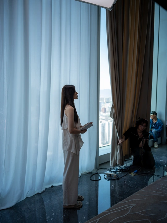 一位站在窗前挂着白色窗帘的女人正在注视着舞台