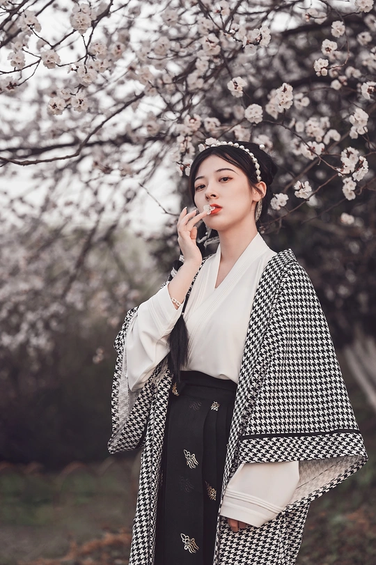 一个穿着外套的年轻女子站在一棵开满鲜花的树前