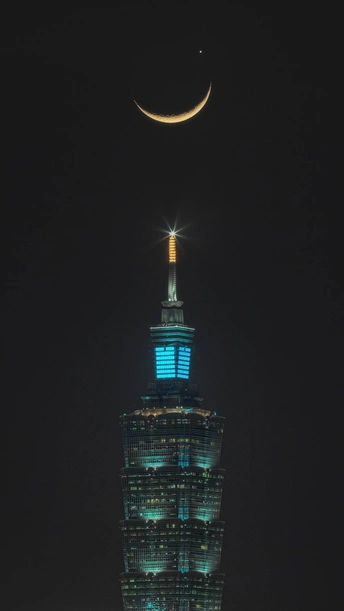 夜晚照亮的高楼 顶部有弯月。
