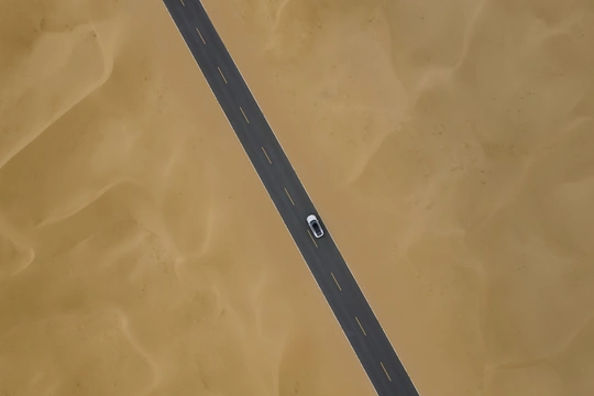 空中拍摄的高速公路上有汽车驶过黄色沙地和水面。