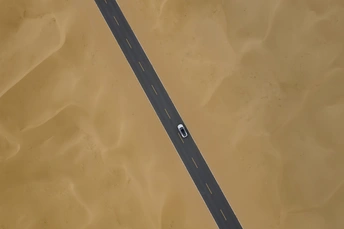 空中拍摄的高速公路上有汽车驶过黄色沙地和水面。