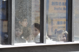 年轻人正在公交车上 透过建筑物的窗户向外看。
