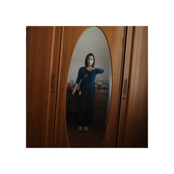 一位戴面具的女子站在镜子前看着自己的脸