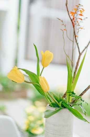 桌子上放着一个装满黄色花朵的白色花瓶
