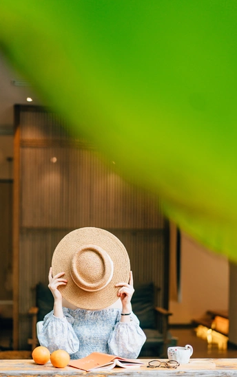 一个戴着大帽子的人坐在放着桔子的桌子旁