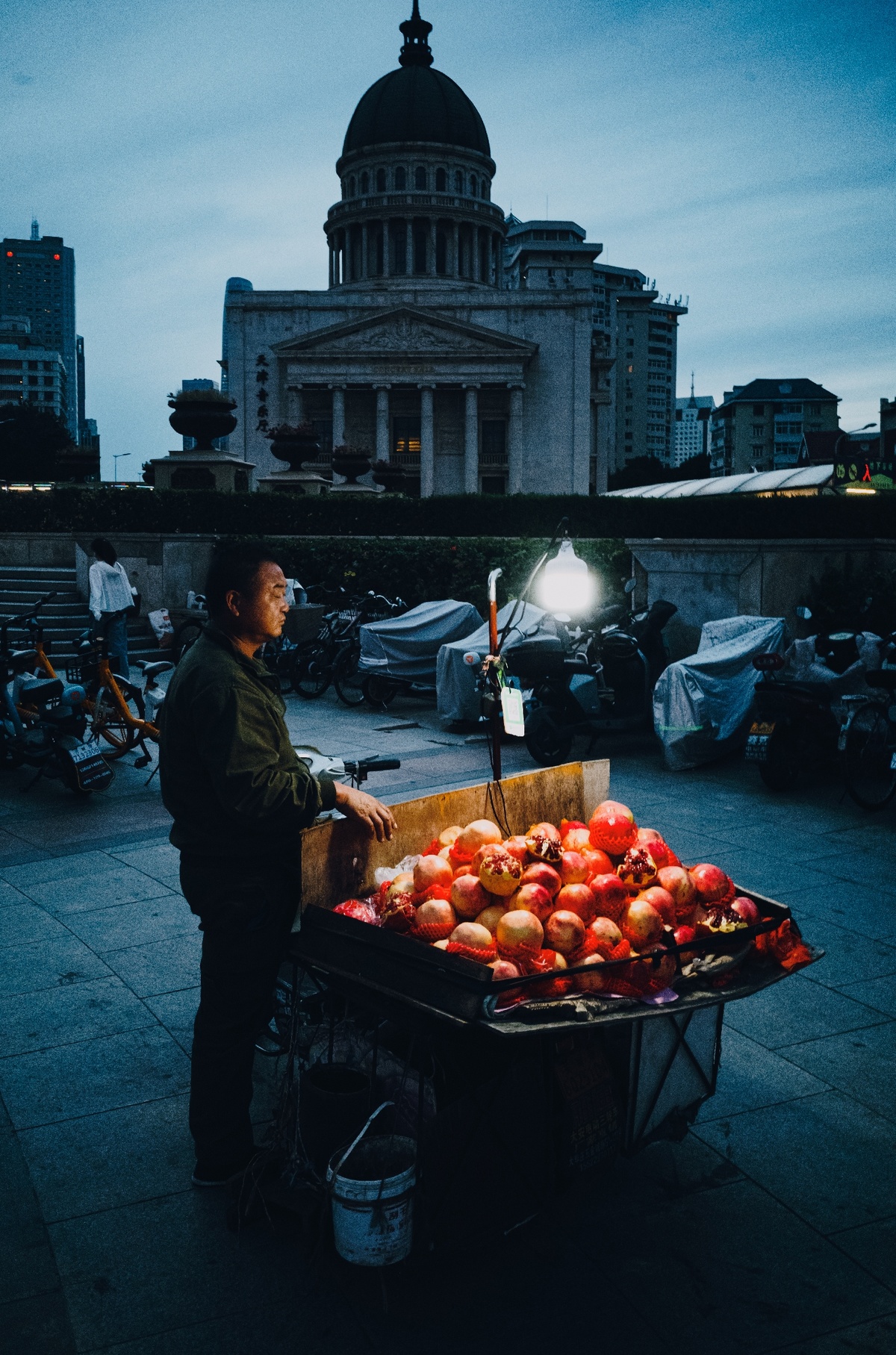站在街边夜晚卖苹果的男子