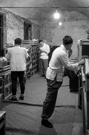 一张黑白照片 一个站在一间房间里的男人 其他工人在工厂里工作。