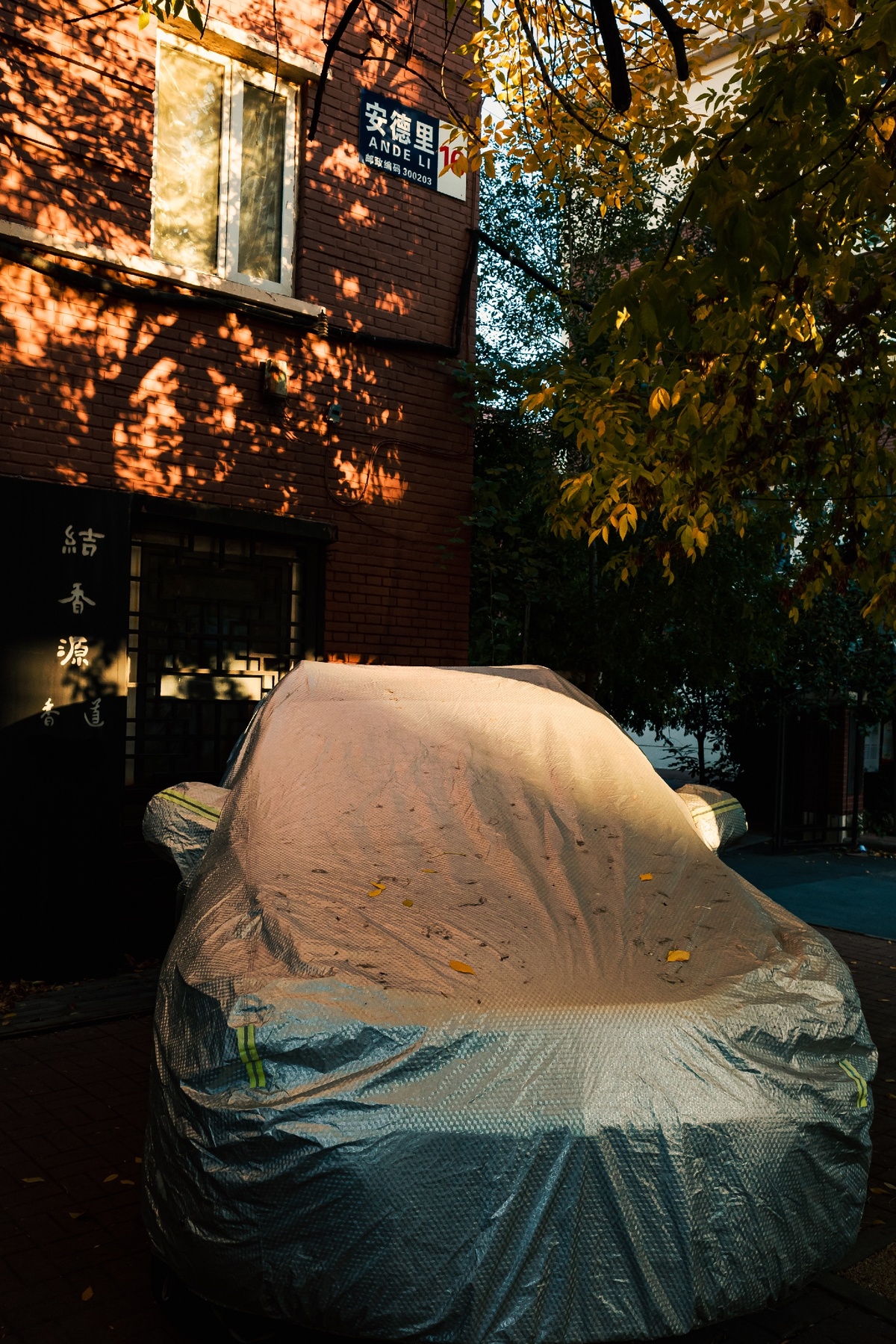一辆停在建筑物前的覆盖着塑料的汽车
