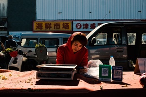 一位妇女坐在桌子旁出售食物