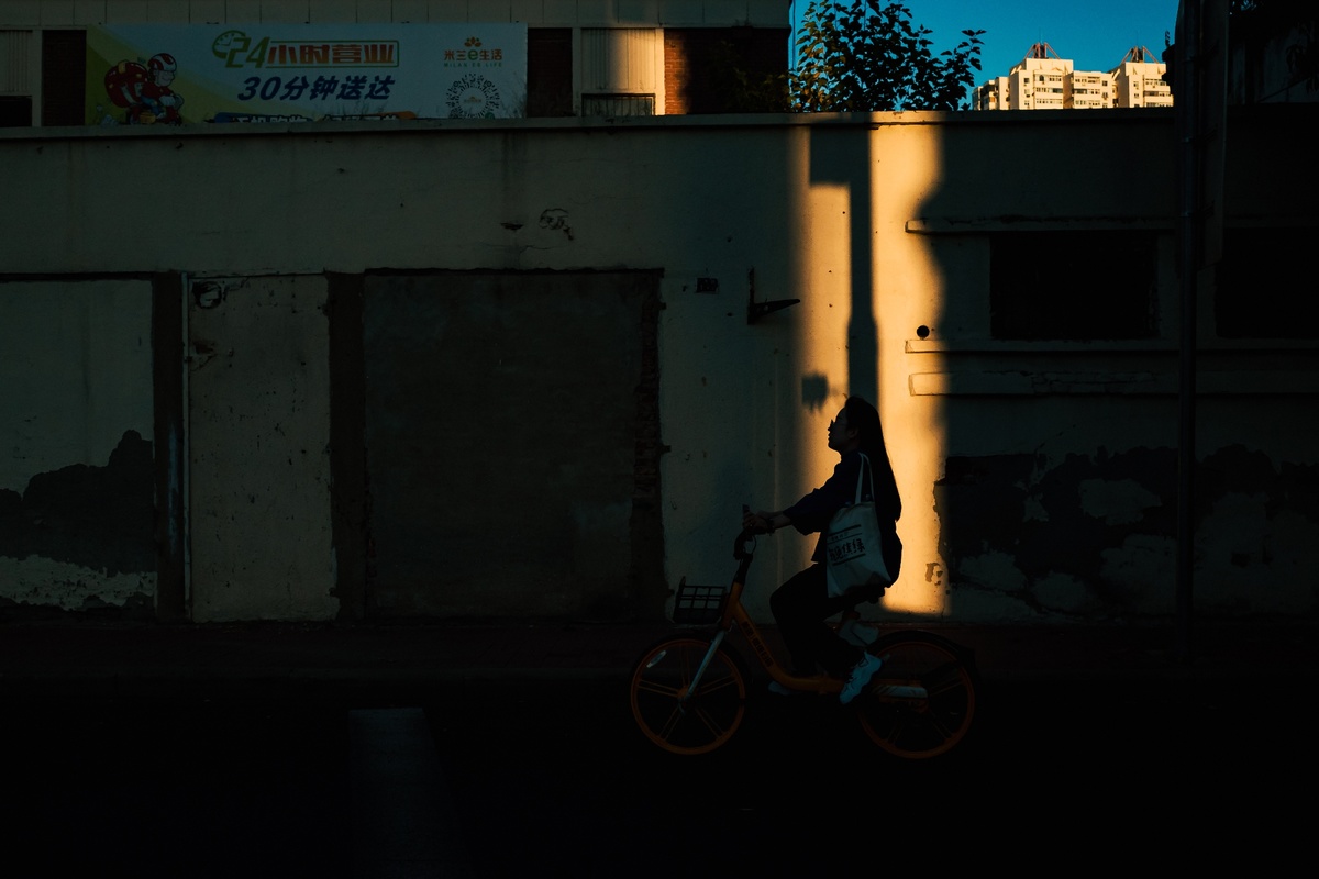 一个人骑自行车在夜晚沿着一条黑暗的街道