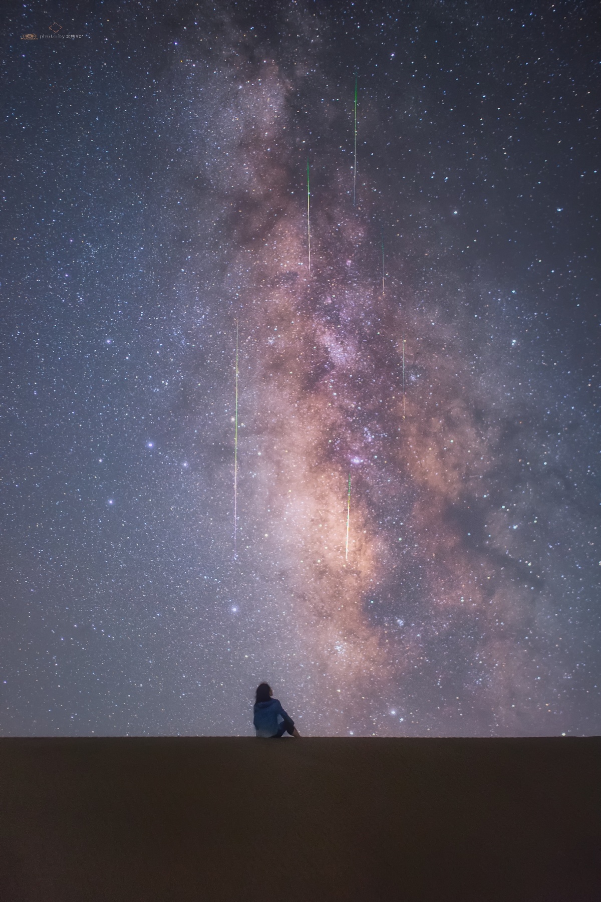 一个独自坐在沙漠中仰望星空的男子 一只鸟儿仰望星空。