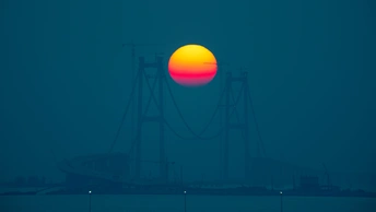 夕阳西下 一座桥和远处的小船在水面上。