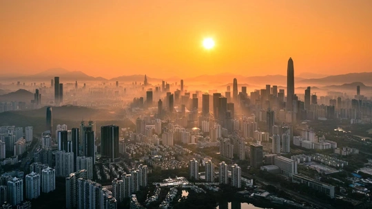 夕阳西下时 太阳落在一个城市的地平线上 前景中有高大的建筑。