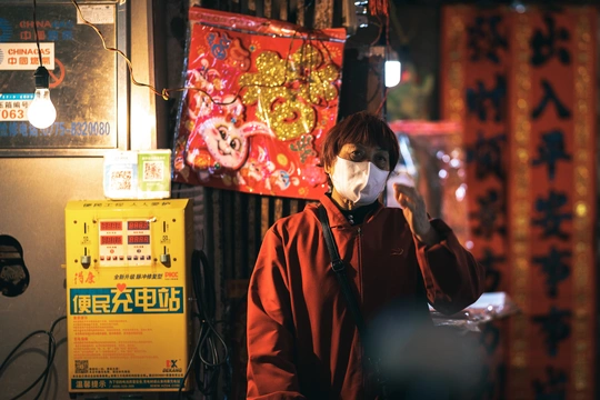 一个戴红夹克的女人正在打电话 一个戴面具的男人在他的脸上